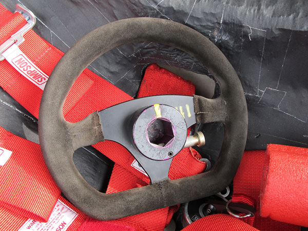 Alpha 255mm flat-bottom suede-covered steering wheel, mounted on a quick release hub.