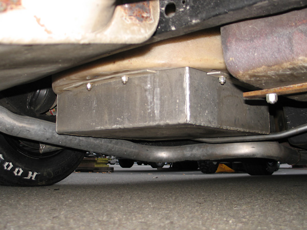 The aluminum fuel cell housing protrudes through the floor of the spare tire well.