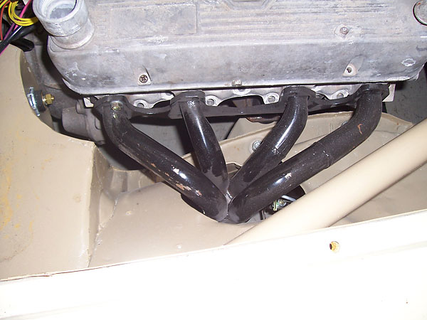 On both sides, the headers exit through holes in the inner fenders (RV8 style).