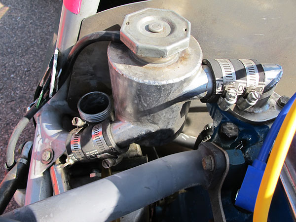 Aluminum header tank / swirl pot. Coolant routes to the nose-mounted radiator through frame tubes.