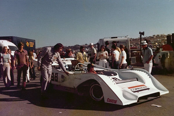 John Cannon helps push his McLaren M8F through the paddock at Laguna Seca.