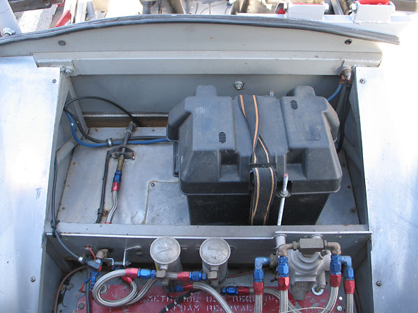 A large lead-acid battery is mounted in a marine battery box, behind the seat.